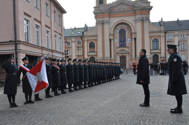 Premier Mateusz Morawicki stoi wraz z dowódcą uroczystości przed funkcjonariuszami celnymi zgromadzonymi na placu
