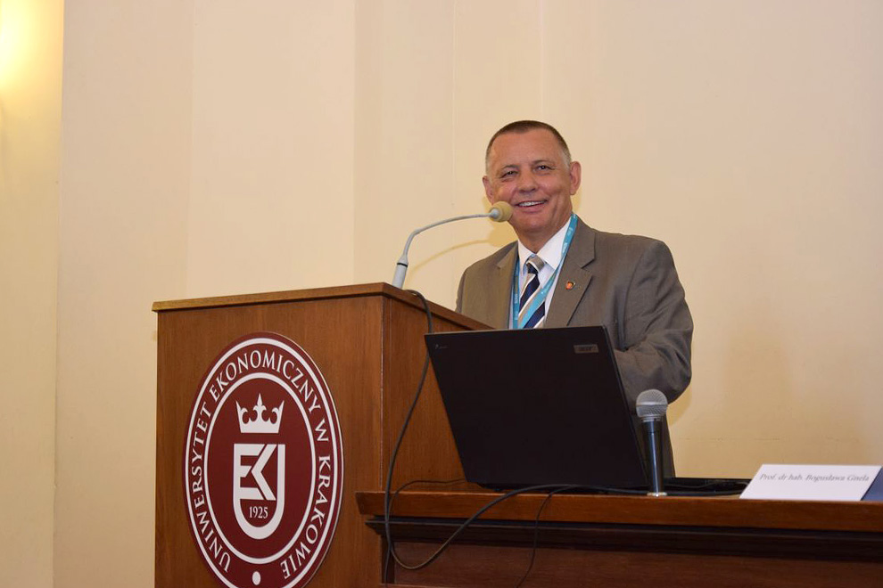 Szef KAS Marian Banaś podczas wystąpienia, napis na ambonie Uniwersytet Ekonomiczny w Krakowie.