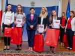 Minister Izabela Leszczyna wśród kolejnej grupy laureatek konkursu, które eksponują otrzymane dyplomy.