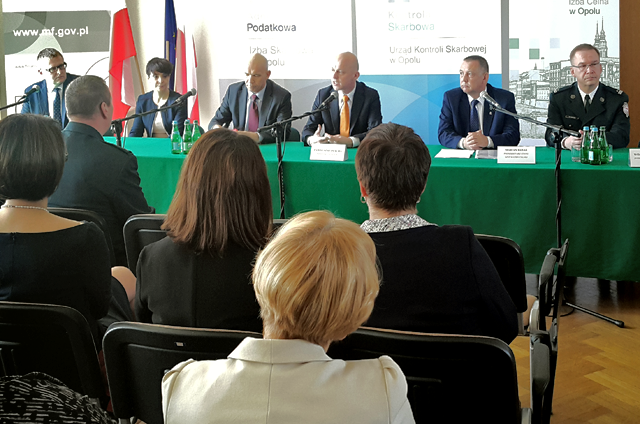 Minister finansów Paweł Szałamacha siedząc za stołem prezydialnym przemawia podczas spotkaniu z przedstawicielami kontroli skarbowej, administracji podatkowej i Służby Celnej województwa opolskiego