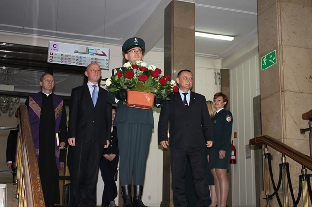 Minister Paweł Szłamacha oraz Szef Służby Celnej Marian Banaś w asyście funkcjonariuszy celnych składają kwiaty pod tablicą pamiątkową. 