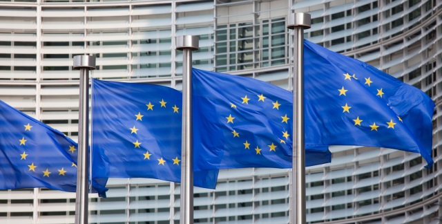Cztery flagi Unii Europejskiej na tle budynku KE