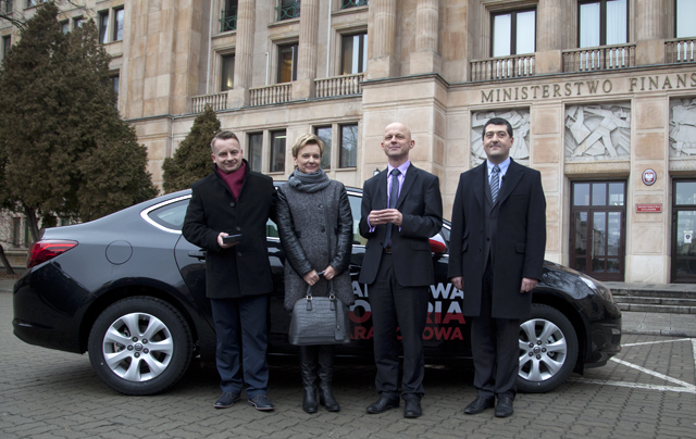 Minister Finansów Paweł Szałamacha i wiceminister Leszek Skiba wraz z zwycięzcami pierwszego losowania Narodowej Loterii Paragonowej stoją przed wygranym samochodem.