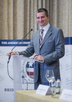 Minister Mateusz Szczurek stoi uśmiechnięty za mównicą podczas spotkania w Amerykańskiej Izbie Handlowej, 5 luty 2014 r., fot. Jacek Domiński, Agencja Fotograficzna Reporter