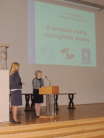 Za mównicą przedstawicielka Urzędu Skarbowego w Mińsku Mazowieckim, wyróżnionego w konkursie Profesjonaliści w służbie obywatelom, w tle tablica z napisem O przyszłe mamy szczególnie dbamy, fot. DSC KPRM