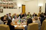 Spotkanie ministra Mateusza Szczurka z członkami ECON, uczestnicy spotkania rozmawiają siedząc za stołem, w tle portrety poprzednich ministrów finansów RP