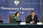 Na zdjęciu siedzący za stołem przed mikrofonami członkowie misji MFW w Polsce Julie Kozack oraz James Roaf, w tle napis Ministerstwo Finansów