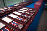 Odznaki Honorowe za Zasługi dla Skarbowości RP leżą w szeregu na stole gotowe do wręczenia