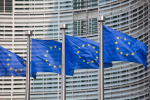 Flagi Unii Europejskiej na masztach przed wieżowcem 