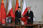 Minister Paweł Szałamacha wymienia uścisk dłoni z prezesem Państwowego Urzędu Podatkowego Jun Wang po podpisaniu porozumienia na tle flag Polski oraz Chin.