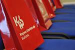 Czerwone torebki na fotelach znajdujących się na sali konferencyjnej w MF a na nich napis KAS - Krajowa Administracja Skarbowa
