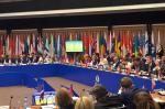 Uczestnicy spotkania podczas posiedzenia plenarnego Europejskiego Banku Odbudowy i Rozwoju na tle flag.
