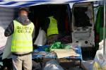 Funkcjonariusze Krajowej Administracji Skarbowej dokonują inwentaryzacji zatrzymanych podróbek towarów znajdujących się w busie na parkingu w Wólce Kosowskiej