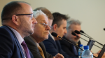 Prowadzący konferencję siedzą przy stole prezydialnym.