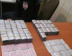 skonfiskowane leki w opakowaniach ułożone na stole, obok funkcjonariusz celno-skarbowe.