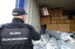 Na zdjęciu funkcjonariusz Służby Celno-Skarbowej przed otwartym kontenerem z nielegalnymi papierosami