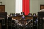 Premier Mateusz Morawiecki przemawia w Sejmie na tle biło czerwonej flagi