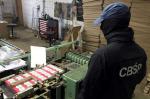 Na zdjęciu funkcjonariusz CBŚP przy maszynach do produkcji papierosów.
