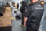 Funkcjonariusze Służby Celno-Skarbowej i Policji, aresztowane osoby na ziemi, kartony z zabezpieczonymi lekami.