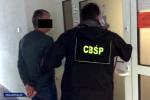 Funkcjonariusz CBŚP z zatrzymanym przed drzwiami.