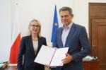 Uśmiechnięta Minister Teresa Czerwińska wraz z nowym podsekretarzem stanu Filipem Świtałą trzymającym w dłoniach akt powołania.     