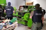 Funkcjonariusze Służby Celno-Skarbowej i Policji przy maszynie do produkcji papierosów.