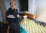 Funkcjonariuszka Służby Celno-Skarbowej przy zabezpieczonych butelkach z alkoholem.