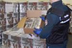 Funkcjonariusz Służby Celno-Skarbowej pokazujący wnętrze pudełka z papierosami.